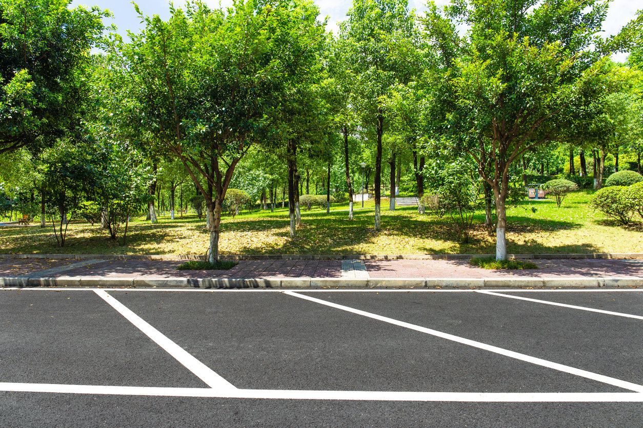 asphalt parking lot with trees in background